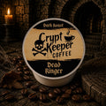 A single round coffee pod package labeled 'Crypt Keeper Coffee' and 'Dead Ringer' sits on a dark textured surface surrounded by coffee beans, with a candle and stone archway in the background.