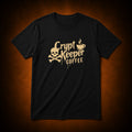 A black short-sleeve crewneck t-shirt featuring a distressed gold graphic that reads 'Crypt Keeper Coffee' alongside a skull and crossbones and a coffee cup icon, displayed against a dark brown textured background.